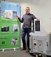 Mann står ved siden av industrielt filtreringsutstyr og en grønn produktvegg.
