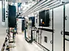 Teknisk rom med elektriske skap, rør og kabler langs en smal gang.