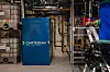 Blå Thermal Box fra Cartesian omgitt av rør og teknisk utstyr i et teknisk rom.